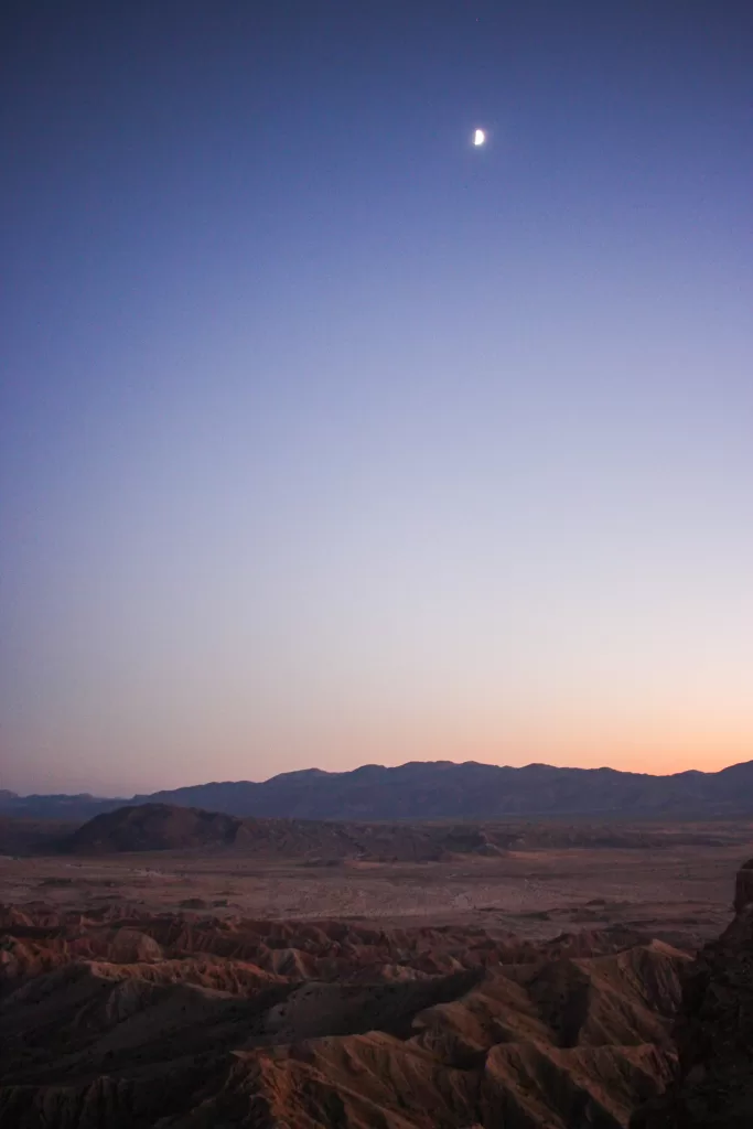 the moon shining over Fonts Point as the sun sets. 