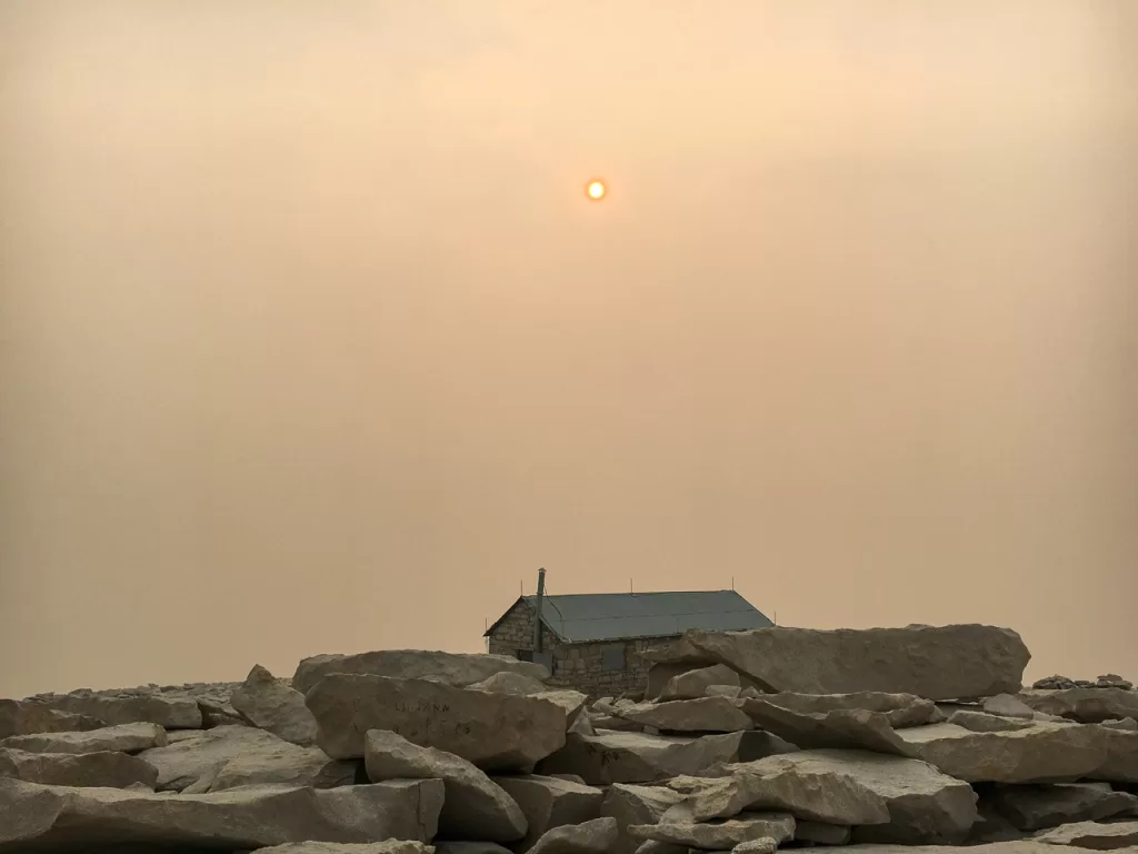 The summit of Mount Whitney, with the sky covered in red hazy wildfire smoke. 