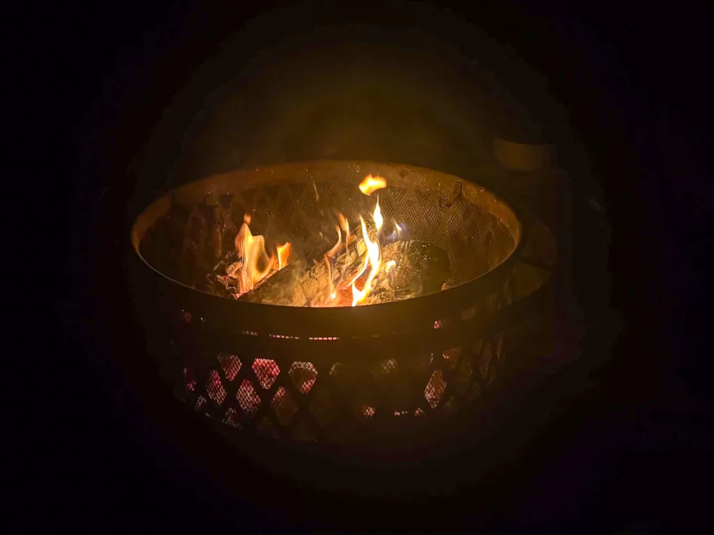 A campfire burning in a metal fire pit. 