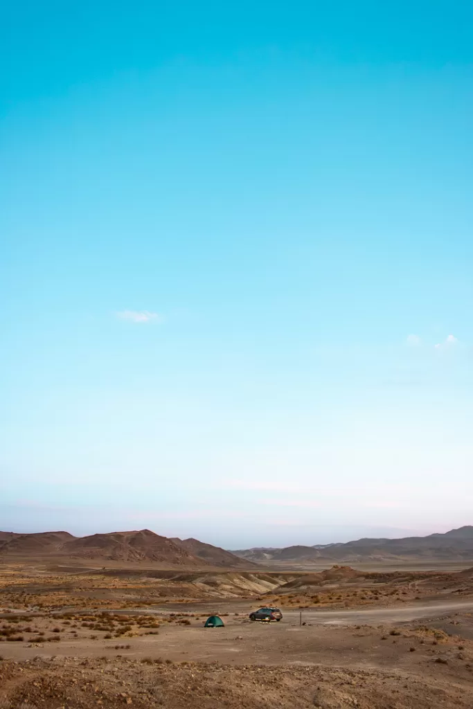 A tent and a car in the desert.