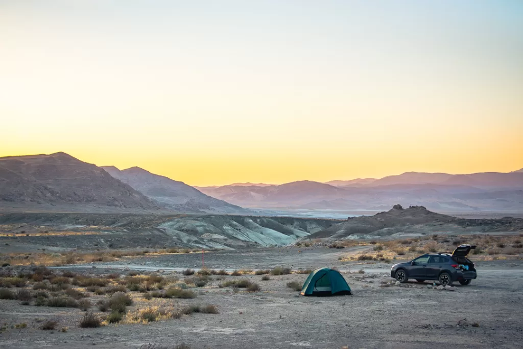 A car and a tent at sunset in the desert. 