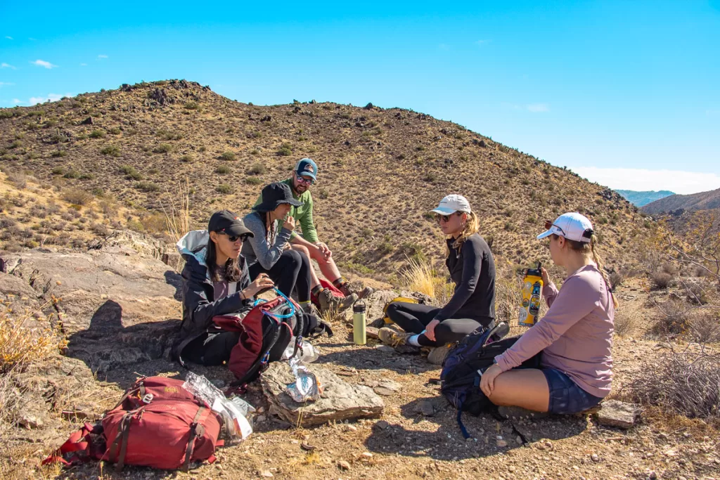 hikers having lunch along the trail, following rule when learning how to hike to bring plenty of food and water, in Joshua Tree. 