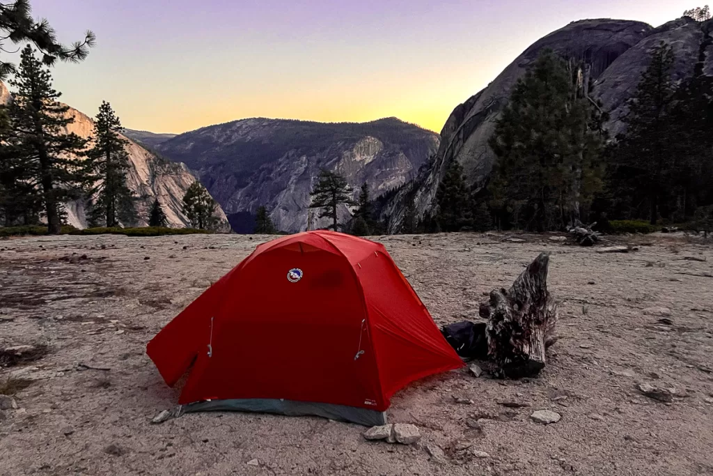 A tent perched on a granite cliff in Yosemite National Park at sunset. 