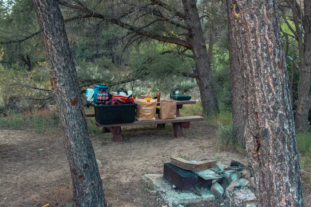 A picnic table with camping gear on it.