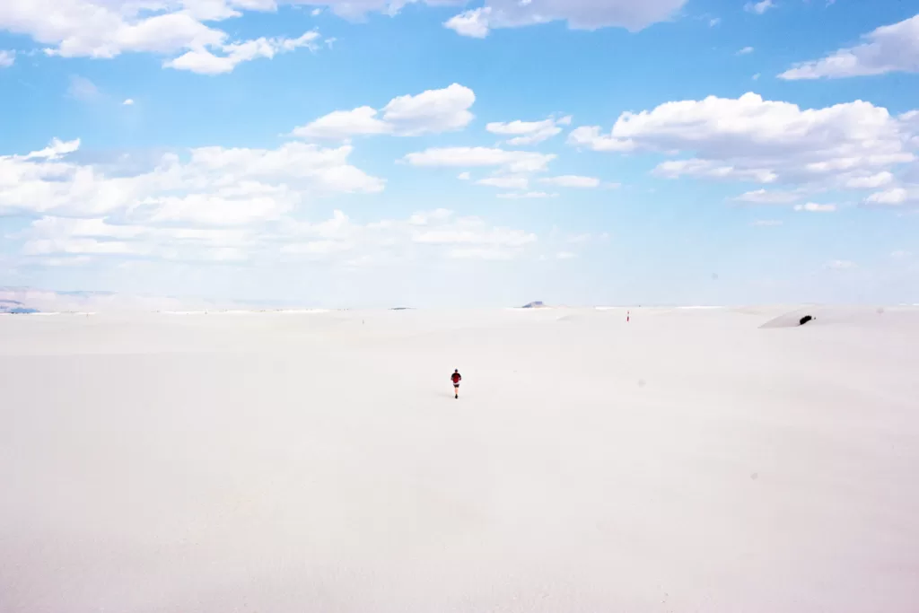 a hiker walking along white sand dunes.