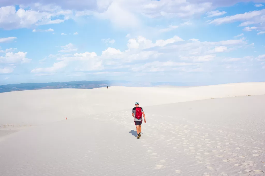 two hikers hiking the Alkali Flat Trail while visiting White Sands National Park.