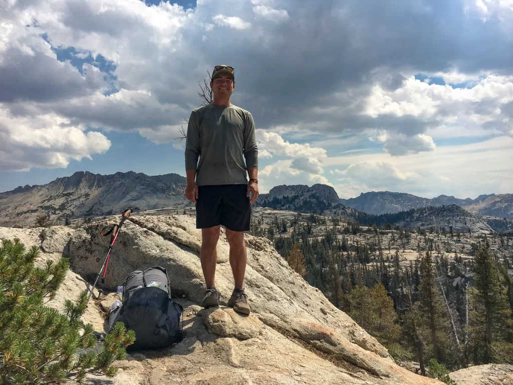 A backpacker smiling at a viewpoint in Yosemite National Park.