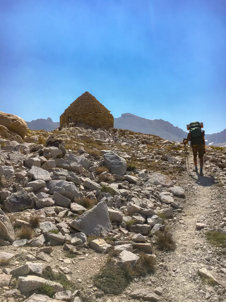 A hiker slowing hiking on the John Muir Trail by Muir Hut. 