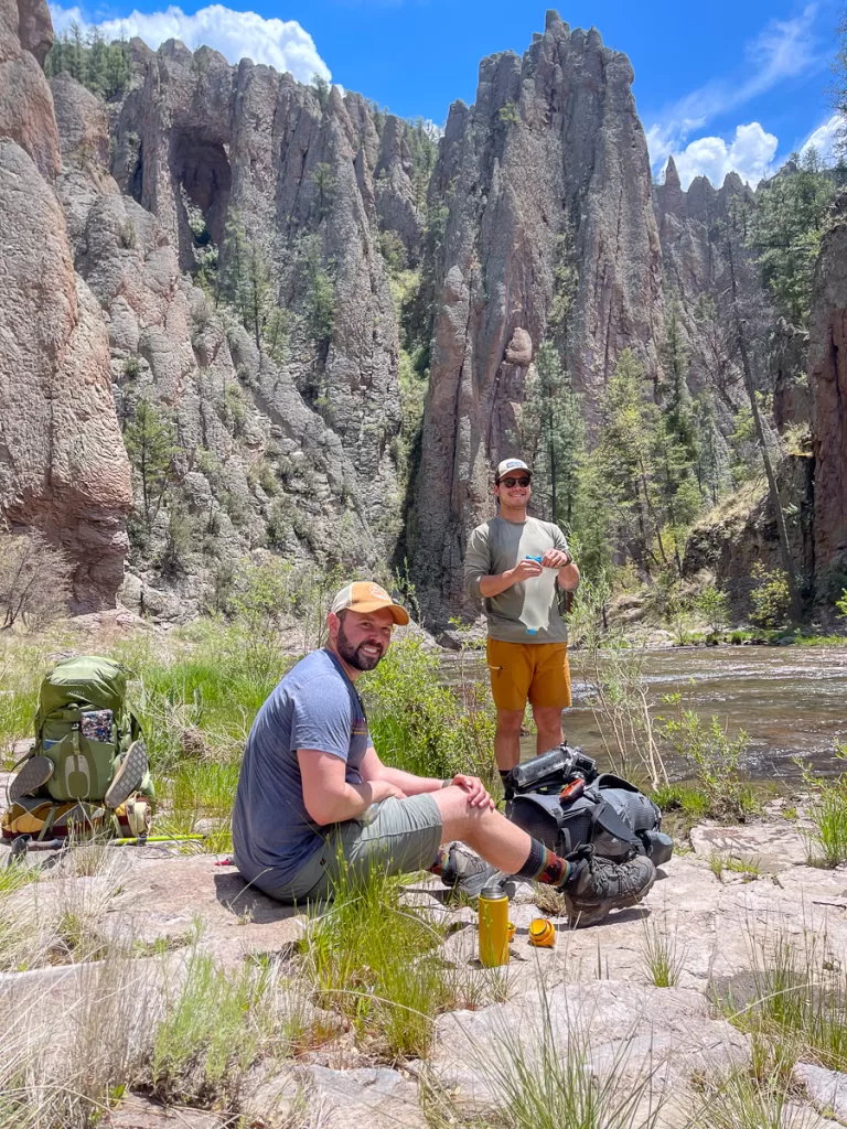 Two hikers resting, one filling up their water. 