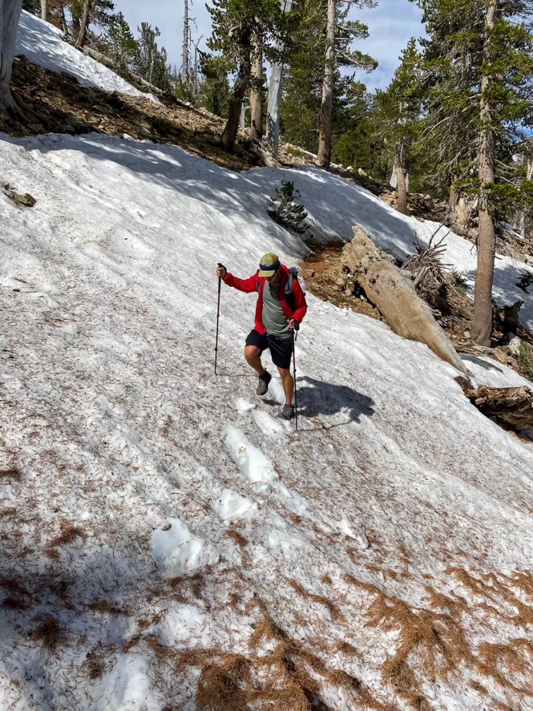 A hiker hiking through snow and who made one of the most common beginner backpacking mistakes of not checking the weather beforehand. 