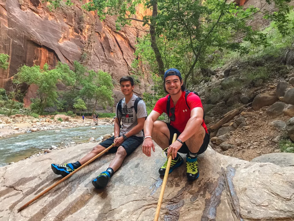 Two hikers siting on a rock by a river.