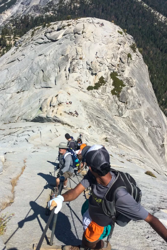 hikers climbing up and down the cables on the hike to Half Dome. 