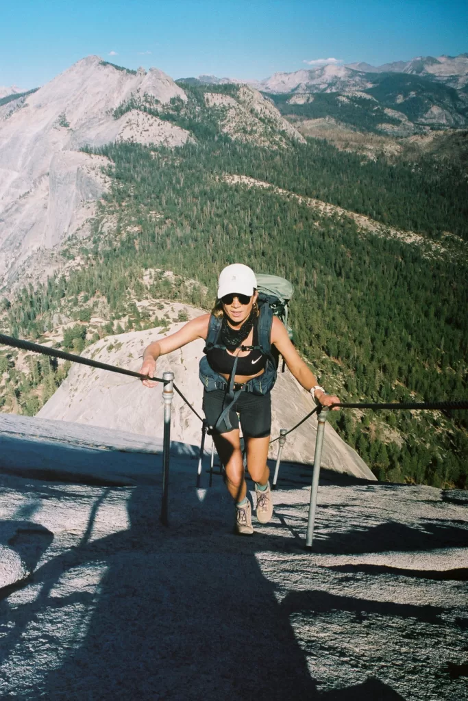 A hiker climbing the cables up to the summit of Half Dome.